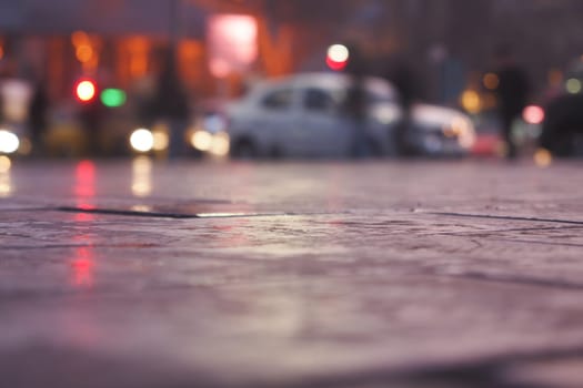 Evening rain creates reflections on the city street at nightfall.