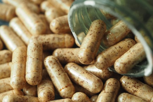 Capsules are scattered across a table, some still in a glass jar.