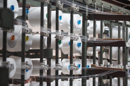 Yarn spools line the machinery as production takes place during work hours.