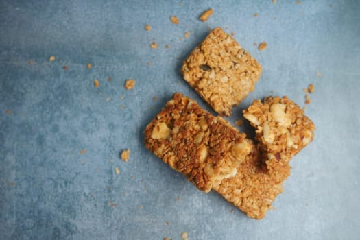 Three crunchy granola bars are scattered on a blue surface.