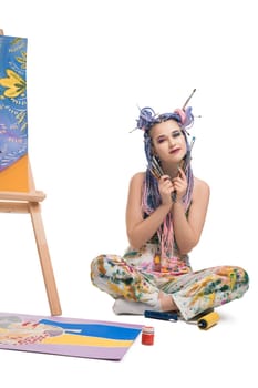 Sexy girl with bright make up in sportswear sitting on the floor near easel isolated view