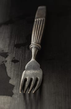 View of Black worn metal vintage fork in dark tone. Ancient vintage fork isolated on black background, Highlighting its texture and design, use it as your Space for text, Design, Wallpaper and Poster, Selective focus.