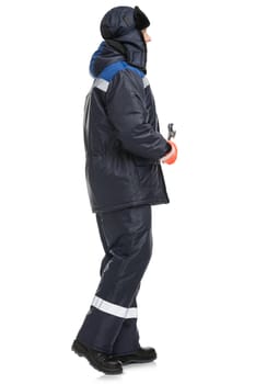 Side view of man in warm blue trousers and jacket with reflective inserts hat on head and wrench in hand isolated on white background