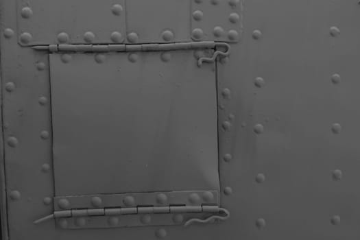 Green metal background with rivets. Side of military equipment with a technical hatch.