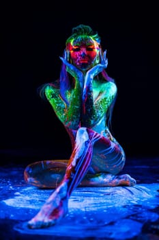 Girl with fluorescent ultraviolet color pattern bodyart posing in dark