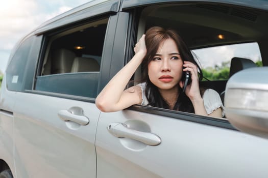 Stressed and confused Asian woman calls insurance on faulty car while traveling together.