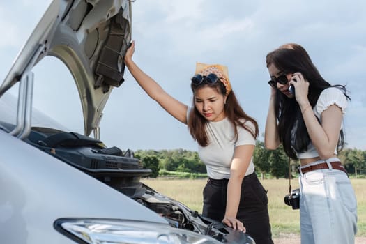 Two stressed and confused Asian women are calling insurance. with a car that has problems While traveling together.