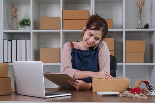 Startup small business entrepreneur SME, asian woman packing cloth in box. Portrait young Asian small business owner home office, online sell marketing delivery, SME e-commerce telemarketing concept.