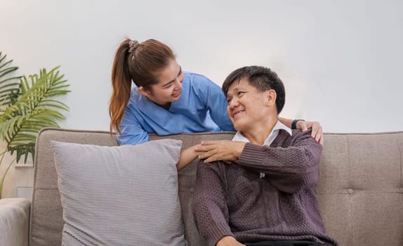 Nurse supports man during recovery A caregiver holds the hand of a senior patient who is resting in the living room