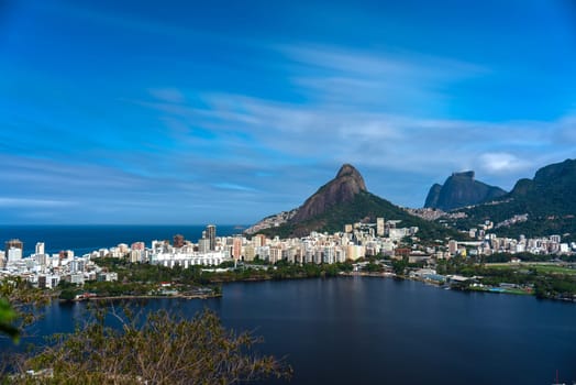 Nighttime long exposure shot of Rio's Lagoa area featuring modern residences, favelas like Rosinha, Dois Irmaos, Pedra Gavea, and water reflections.