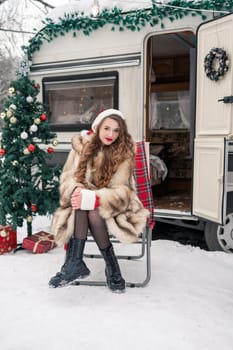 Young woman in fur coat with gift box at winter campsite getting ready for the new year.