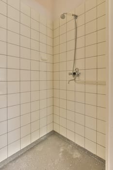 a shower stall with white tiles on the walls and floor in an empty room, it appears to be used as a bathroom