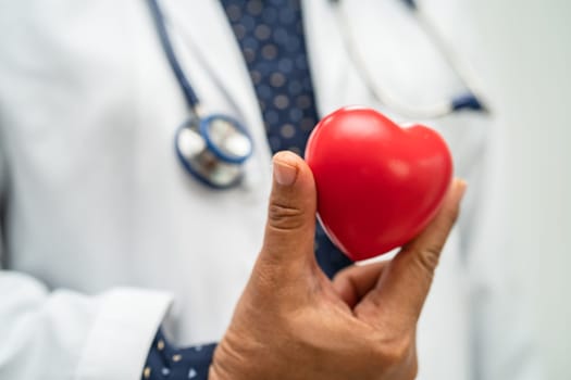 Doctor holding a red heart in hospital ward, healthy strong medical concept.