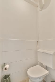 a white toilet in a small bathroom with tiles on the floor and wall behind it, there is a plant next to the toilet