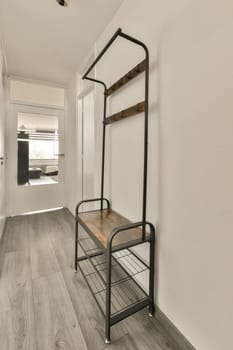 an empty room with wood flooring and white walls, including a black metal rack on the wall above it