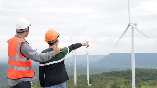 Engineer with his son on a wind farm atop a hill or mountain in the rural. Progressive ideal for the future production of renewable, sustainable energy. Energy generation from wind turbine.