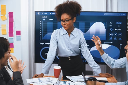 Young african businesswoman presenting data analysis dashboard on TV screen in modern meeting. Business presentation with group of business people in conference room. Concord