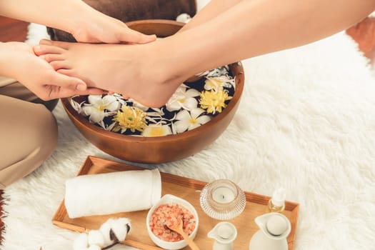 Woman indulges in blissful foot massage at luxurious spa salon while masseur give reflexology therapy in gentle day light ambiance resort or hotel foot spa. Quiescent