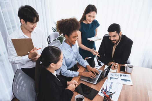 Multiracial analyst team use BI dashboard data to analyze financial report on meeting table. Group of diverse business people utilize data analysis by FIntech for success business marketing. Concord