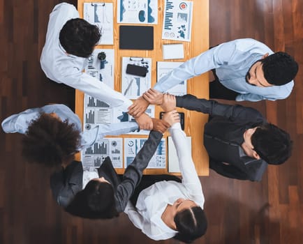 Top view diverse team of officer workers hold hands in circle, showing solidarity and teamwork in corporate office. Businesspeople form strong community built on integrity and collaboration. Concord