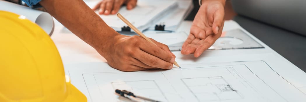 Engineer partner drawing and working on blueprint design together on office table for architectural building construction project. Architect drafting interior blueprint layout. Insight