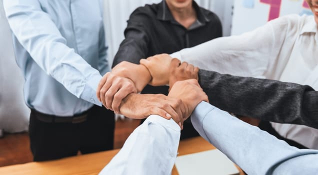 Diverse team of officer workers hold hands in circle, showing solidarity and teamwork in corporate office. Businesspeople form strong community built on integrity and collaboration. Concord