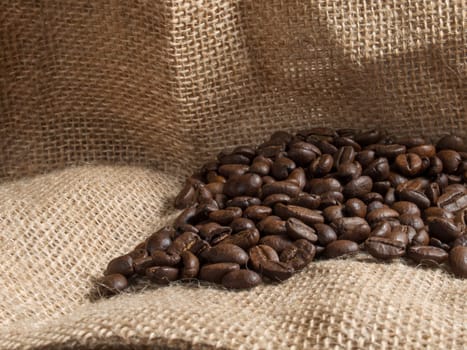 Brown roasted coffee beans on sackcloth.