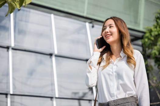 Happy businesswoman working talking on smartphone outdoor in city with client, Asian business female calling on smart mobile phone and walking on street outside office building, business communication