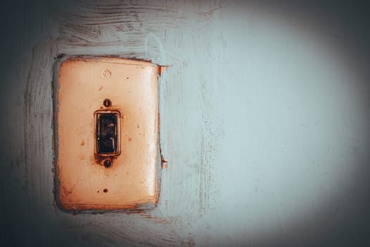 This image features a vintage light switch set against a textured blue wall, highlighting elements of nostalgia and the charm of retro design in everyday objects.