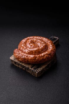 Delicious homemade sausage in the shape of a snail or spiral, with salt and spices on a dark concrete background