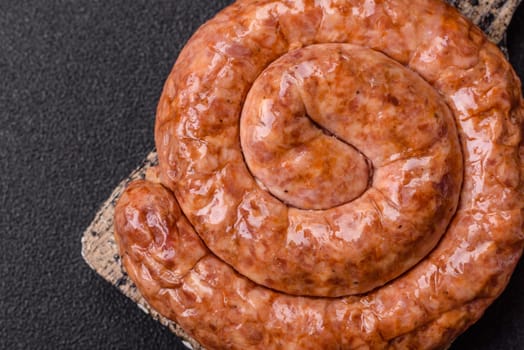 Delicious homemade sausage in the shape of a snail or spiral, with salt and spices on a dark concrete background