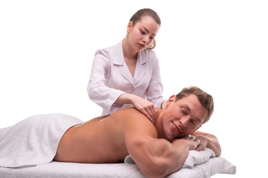 Concentrated professional female massaging back of content male customer resting on table in salon
