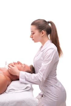 From above of crop masseuse massaging chin of relaxed male customer lying on table in spa center