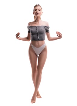 Full body of sensual female in panties standing with closed eyes in studio on white background