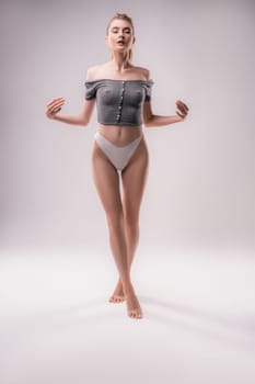 Full body of sensual female in panties standing with closed eyes in studio on white background