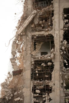 Exterior of abandoned concrete high rise building with broken crumbling walls against gray sky