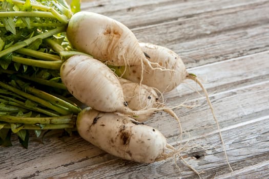 Several large chinese radishes displayed on wood.