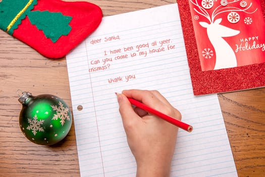 Picture of a child's hand writing a letter to Santa.