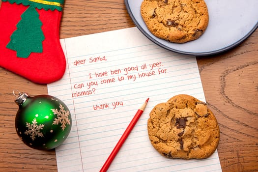 A close up image of a letter to Santa, cookies, and a few decorations.