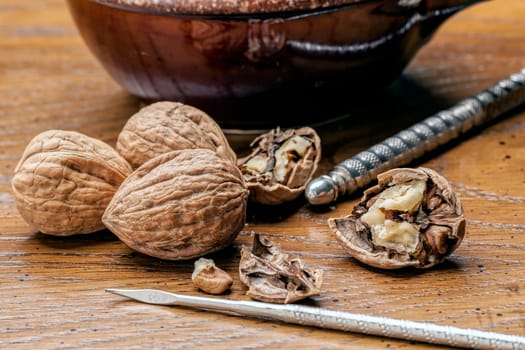 Unshelled and shelled walnuts on the table with a pick and nutcracker.