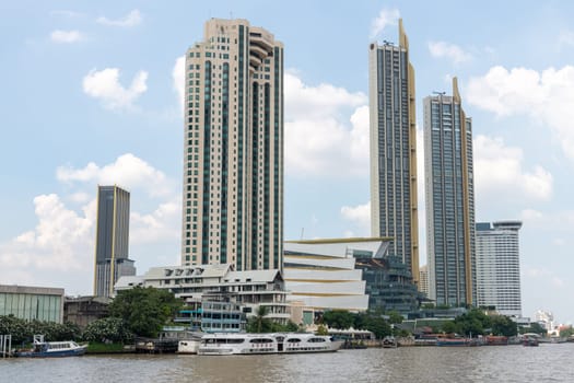 A breathtaking modern skyline displaying impressive tall buildings situated along a serene river beneath a bright sky