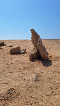 Close up of a row of stones stands in the desert, used as a direction for movement.