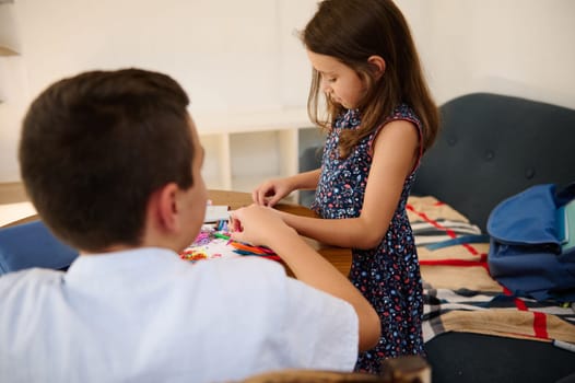 Two children are creating art together in a cozy indoor setting, fostering creativity and teamwork.