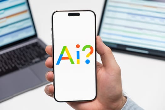 PRAGUE, CZECHIA - JULY, 2024: Google AI logo on the screen of smartphone in mans hand and laptop on the background