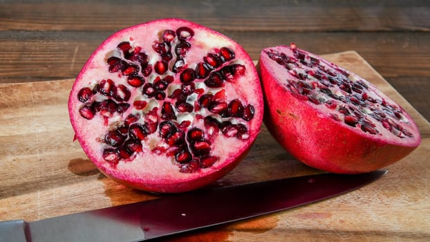 Fresh cut pomegranate halves on wooden cutboard