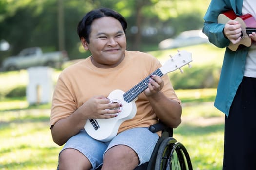 A young man with a disability joyfully playing a ukulele in a sunny park, enjoying music while engaging with a friend, emphasizing inclusion and happiness.