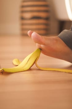 Foot unexpectedly encounters a banana peel on a wooden floor.