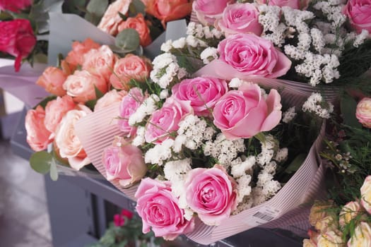 Bright pink roses are beautifully arranged with white flowers in a shop.