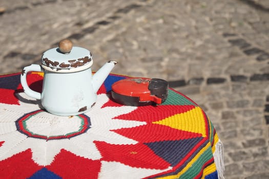 A vintage teapot sits on a vibrant circular table, illuminated by sunlight.