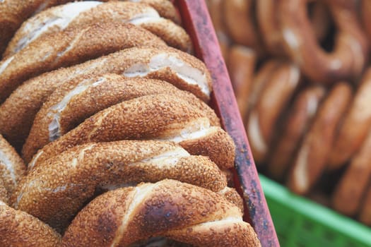 Fresh simit rolls with sesame seeds are stacked in vibrant baskets.